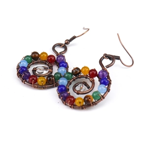 Detailed macro view of handmade boho spiral wire earrings with multicolor chakra beads