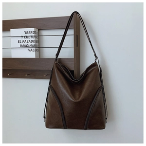 Close-up of vintage dark brown PU leather tote bag with decorative front zippers