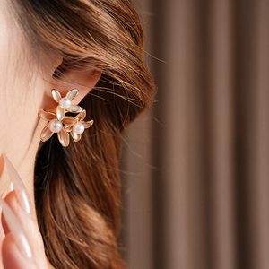 Close-up of gold plated flower earrings with translucent petals and pearl centers