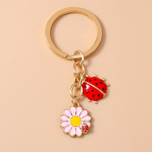 Detailed close-up of golden keychain with red ladybug and pink flower charms