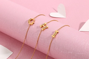 Detail of gold letter G H I pendants with sparkling crystals on a stylish chain