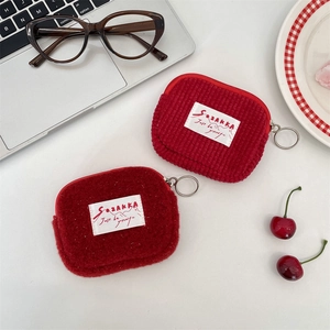 Close-up of red plush and corduroy storage pouches for lipstick, earphones, and cards