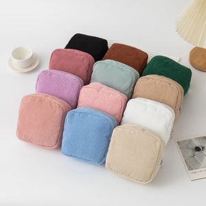 Detailed view of various colorful corduroy cosmetic bags arranged on a white desk