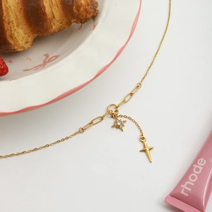 Détail du collier étoile en acier doré avec chaîne trombone et croix en cristal