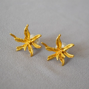 Vintage gold-plated floral earrings with pearls and matte finish on grey textured fabric