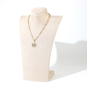 Macro detail of gold chain necklace with retro coin pendant on jewelry display stand
