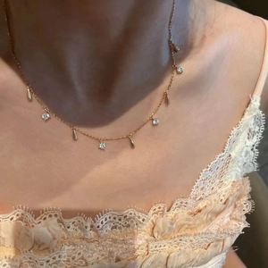 Close-up of gold cross pendant with crystal droplets worn on a model neck