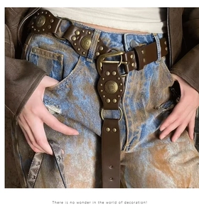 Detail of vintage brown leather belt with gold studs and rings on denim jeans