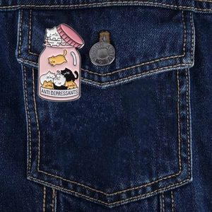 Cute cartoon cat enamel pin in a pink jar on a denim jacket labeled Anti Depressants