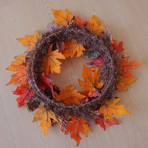 Detailed top view of autumn wreath with orange maple leaves and berries on wooden floor