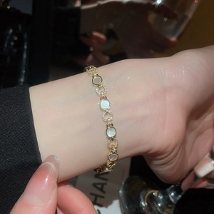 Détail d'un bracelet de luxe doré avec nacre blanche et cristaux de zircon brillants