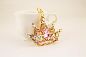 Detail showing a golden crown keychain with pink crystal and sparkling rhinestones