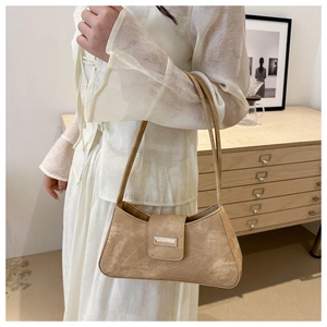 Detailed close-up of brown suede underarm bag featuring a metallic square buckle on strap
