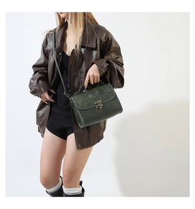 Detail of dark green vintage handbag featuring embossed lotus pattern and bronze lock
