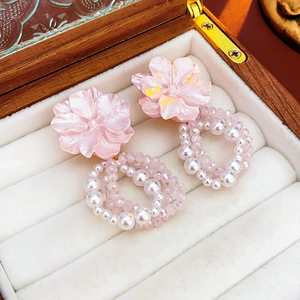 Close-up of pink flower earrings with pearl bead rings on a white velvet jewelry box