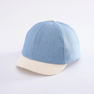 Dettaglio del tessuto denim azzurro e della visiera color crema di un berretto da bimbo