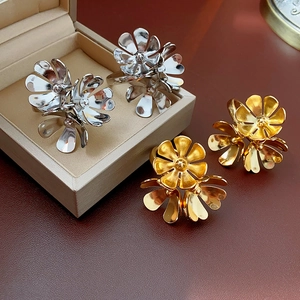 Detailed view of large gold and silver metallic flower earrings in a jewelry box