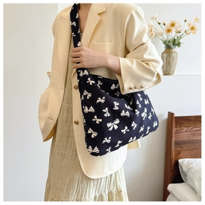 Detail of soft knitted shoulder bag with white bow jacquard pattern and wide strap