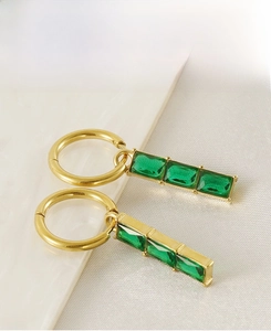 Detail view of 18K gold stainless steel earrings with three green rectangular zircons