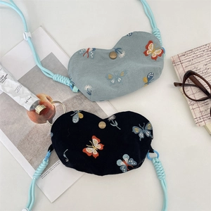 Détail de la pochette papillon brodée en forme de cœur avec bandoulière et bouton pression
