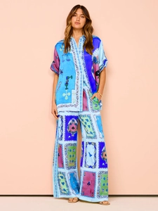 Detail of silk-satin lounge set featuring blue poker print shirt and wide-leg trousers