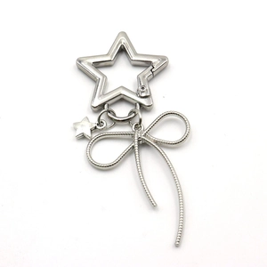 Detail of silver star-shaped keychain with woven bow and small solid star pendant