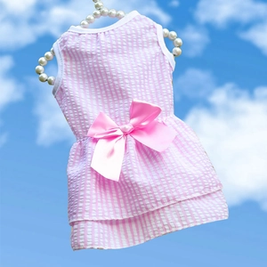 Detail of pink striped pet dress with large bow on a pearl hanger with sky background