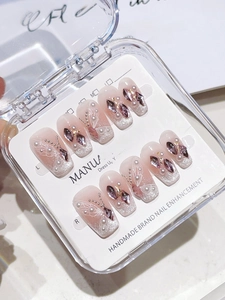 Detail of handmade nude pink press-on nails with butterfly, crystals and pearls in a box