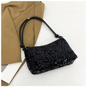 Close-up of black sequined baguette bag with shoulder straps on white background