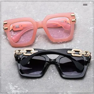 Close-up of oversized sunglasses featuring golden chain link temples and gradient lenses