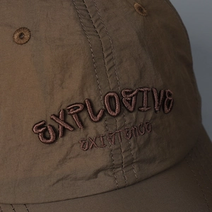 Macro shot of high-quality 3D embroidery detail on dark brown outdoor baseball cap