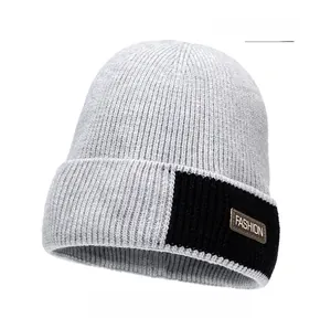 Detail of light gray knit beanie with a brown leather FASHION patch on black label