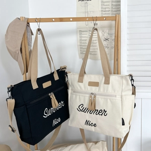 Detail of canvas tote bags in black and cream featuring Summer Nice embroidery