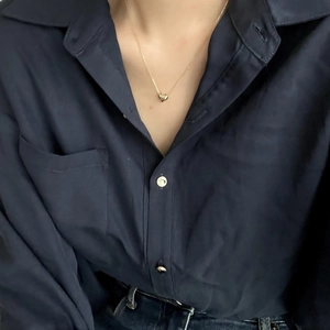 Close-up of a delicate golden heart pendant necklace worn on the collarbone