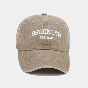 Close-up of white Brooklyn embroidery on washed khaki cotton vintage baseball cap