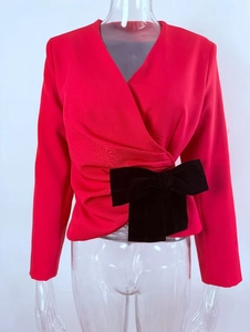 Detail of red V-neck wrap top featuring a large black velvet bow and pleated waist texture