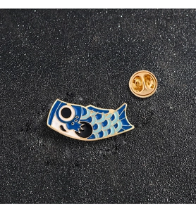 Detailed close-up of Japanese koi fish enamel pins in blue and black with golden edges