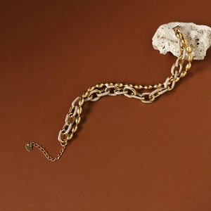 Détail d'un bracelet à perles dorées et maillons blancs sur une pierre de corail blanc