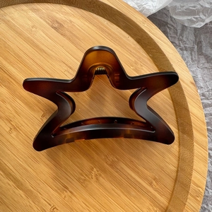Macro detail of star-shaped hair claw clip with brown tortoiseshell pattern and metal spring