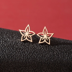 Boucles d'oreilles étoiles évidées dorées pour femme sur fond noir et rouge texturé