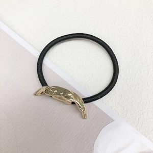 Close-up of minimalist black elastic hair tie with irregular gold metal ornament