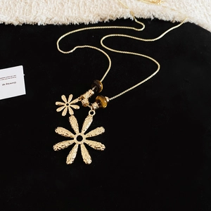 Detailed macro view of handcrafted hammered metal flower pendants and tiger eye beads