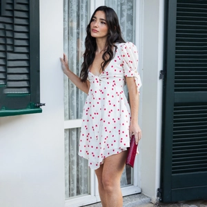 Détail d'une robe blanche à pois rouges avec col en V et manches bouffantes