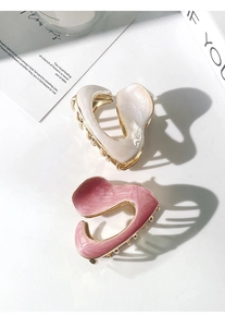 Close-up of cream and pink enamel shark clips with gold metal trim and abstract design