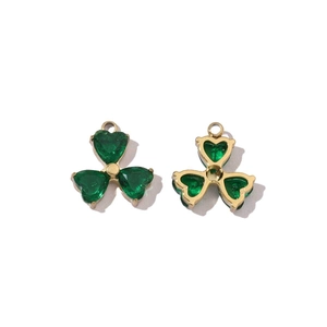 Detail of gold clover pendants with green heart stones showing front and back views