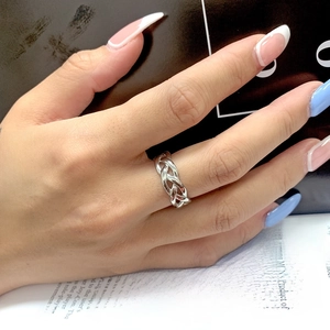 Close-up of a silver braided chain ring on a finger with a stylish magazine background