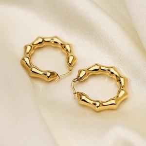 Macro detail of U-shaped bamboo design hoop earrings in polished gold titanium steel