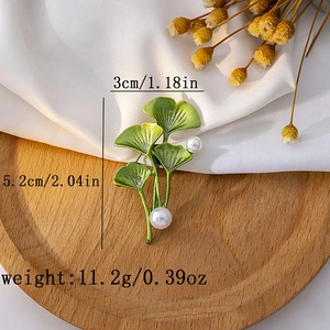 Green ginkgo leaf brooch with pearls on wood tray, measuring 3cm by 5.2cm