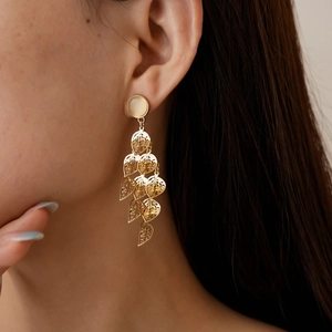 Detailed view of gold leaf drop earrings with cat eye stone worn by a model