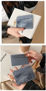 Blue leather card holder with denim texture and gold zipper hardware shown in hand